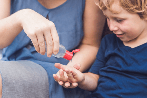 mother teaching child on how to use hand sanitizer and not to swallow it